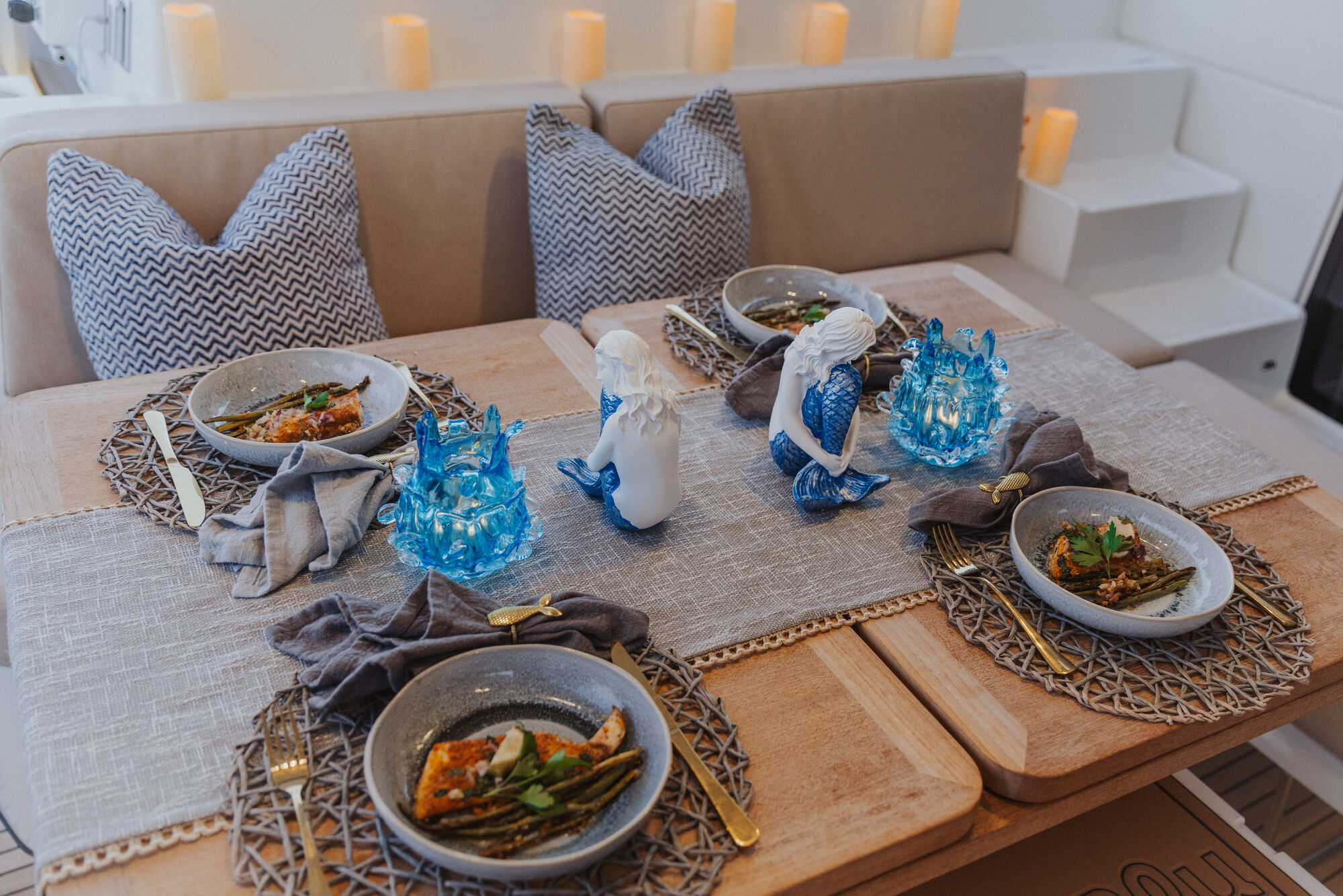 Four beautifully plated bowls with mermaid candleholders and gold flatware
